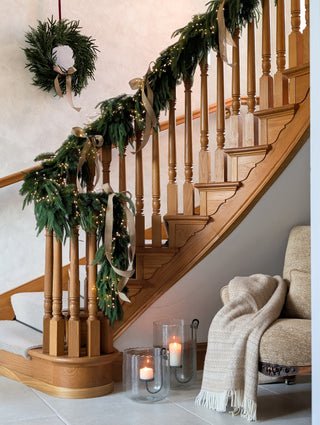 Staircase dressed with a mixed evergreen garland and Christmas wreath