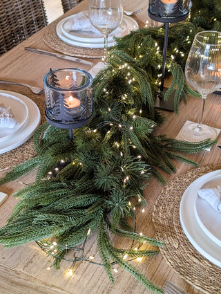 Mixed evergreen garland as a Christmas table centrepiece with candles