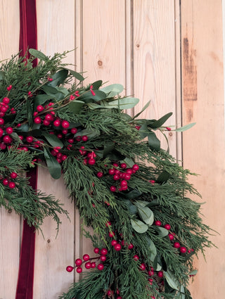 Close detail of olive leaves, eucalyptus and red berries on the large wreath