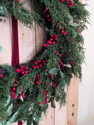 Classic red and green faux Christmas wreath with olive leaves and eucalyptus