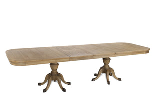 Three-quarter angled view of the Ashbourne dining table at full 310cm extension, showing the twin pedestal base and panelled oak top