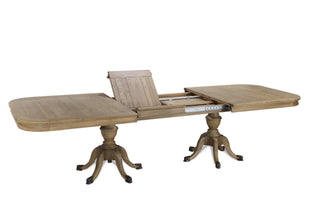 Top-down view of the Ashbourne dining table mid-extension, showing a single oak leaf being lifted into place between the two halves of the top