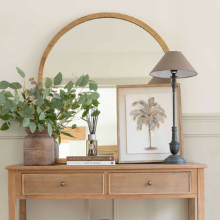 Pembury black table lamp styled on a wooden console table alongside an arched brass-framed mirror, stacked books, framed art and brown vase with foliage