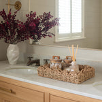 Plum eucalyptus artificial stem displayed in a bathroom vanity with wicker accessories