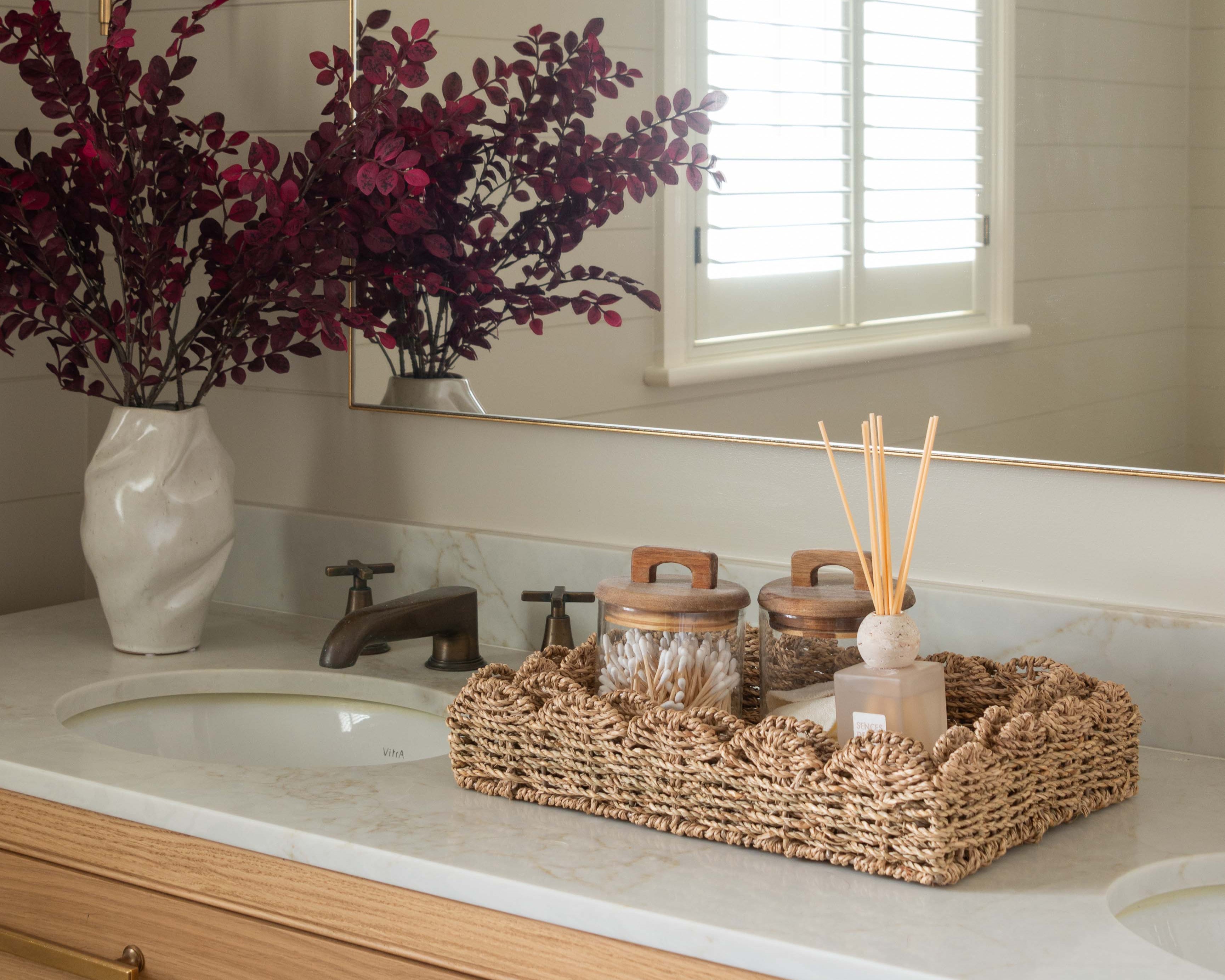 Plum eucalyptus artificial stem displayed in a bathroom vanity with wicker accessories