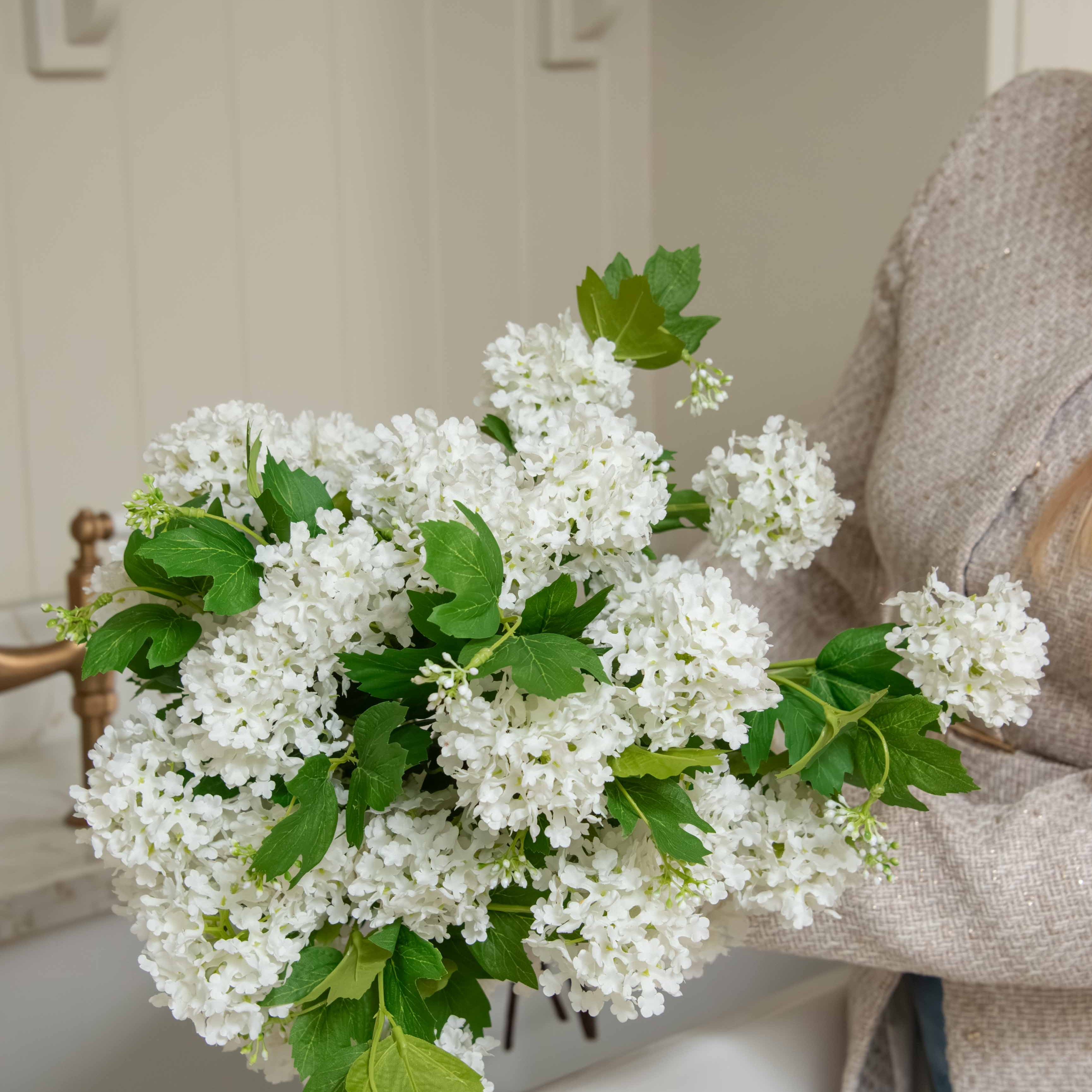 Pom Pom White Viburnum Spray. Its snowball-like floral heads and lush leaves, delicately drooping like the real thing, make for an incredibly lifelike addition to any setting. Use between 6 - 8 stems for a truly impressive impact.