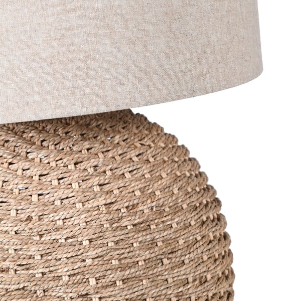 Close-up of a lamp with a textured woven base and beige lampshade.