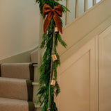 Decorative green garland with brown ribbons and gold ornaments on a staircase.