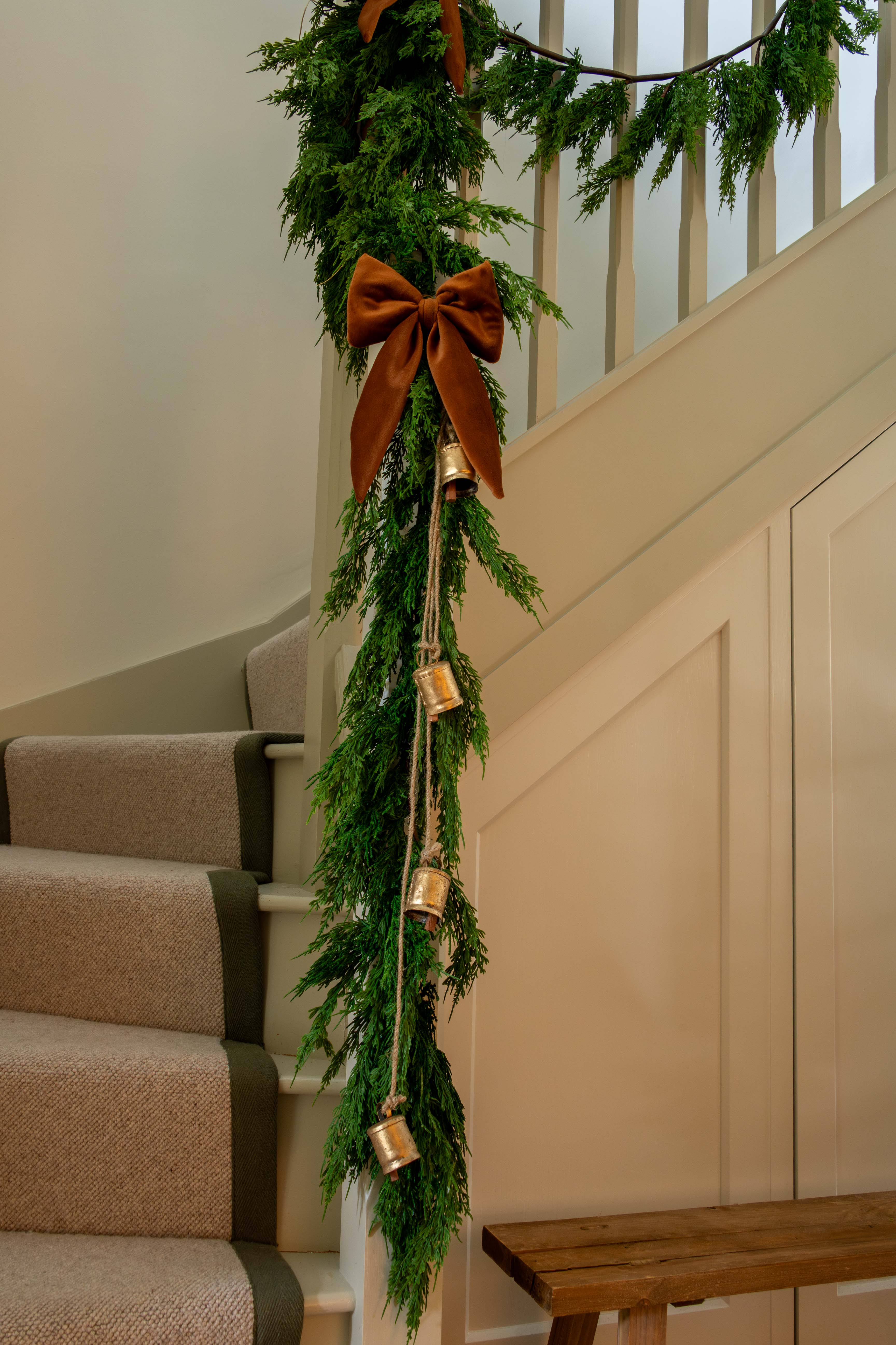 Decorative green garland with brown ribbons and gold ornaments on a staircase.