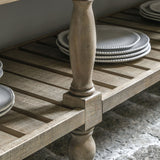 Close-up of slatted bottom shelf with stacked plates on wooden sideboard