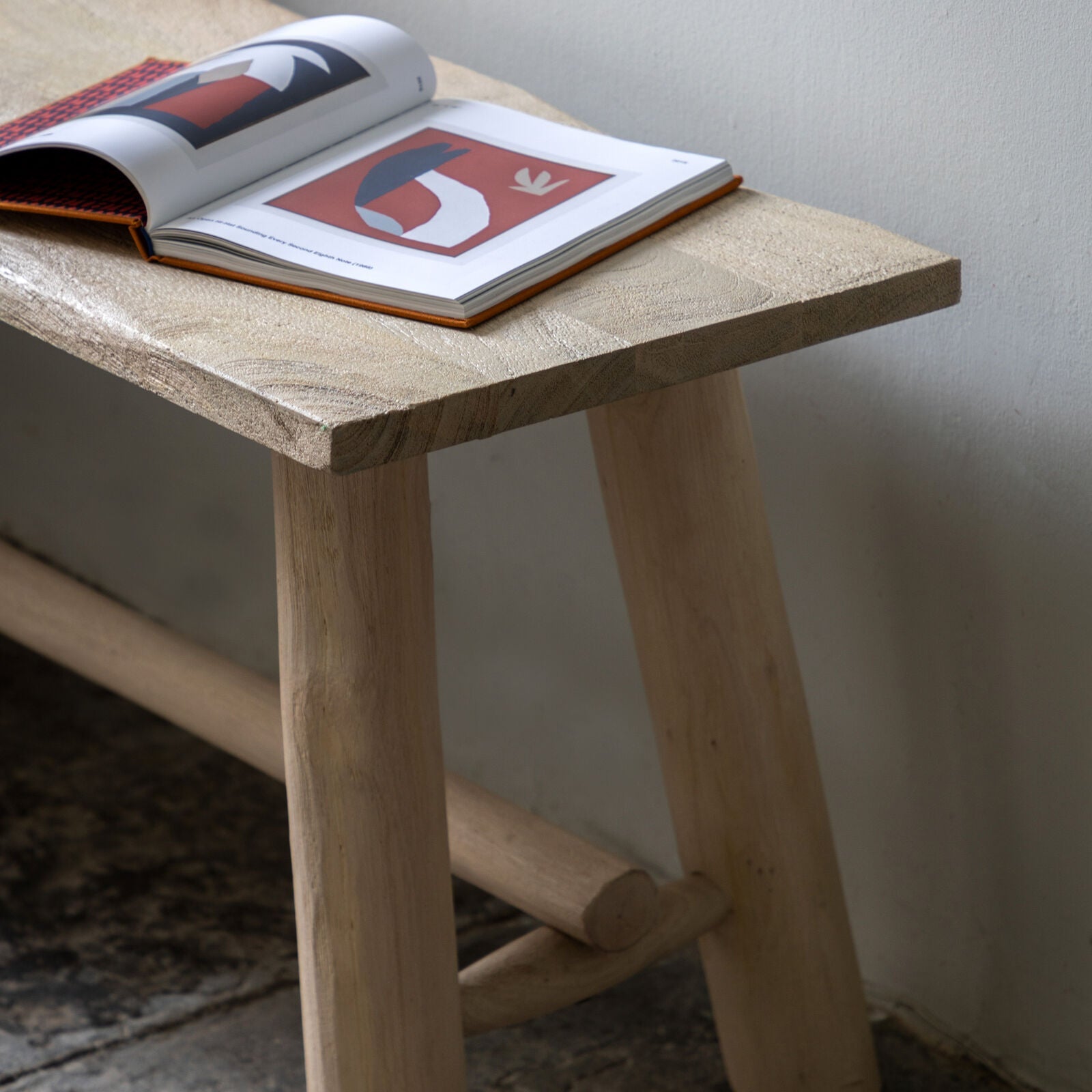 Rustic solid wood farmhouse bench with natural finish and round legs close up