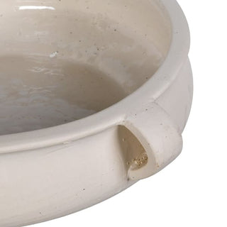 Close-up of a cream-colored ceramic bowl with a small side handle and speckled glaze, shown against a plain white background.