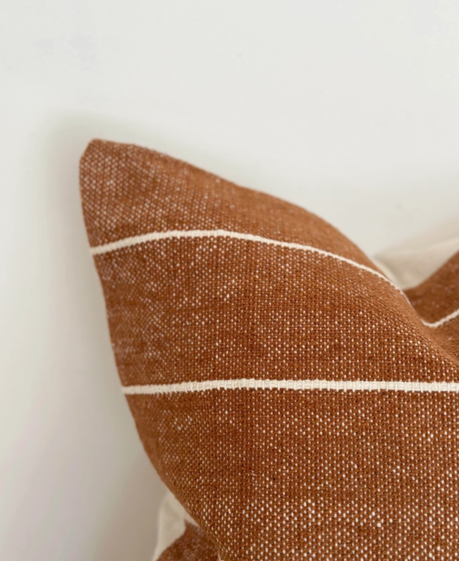 A stunning rust coloured cotton cushion with an off white stripe.