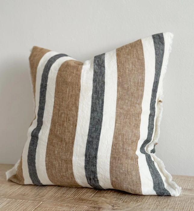 Navy and brown striped cushion cover with linen look fabric displayed on a wooden surface
