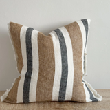 Navy and brown striped cushion cover with linen look fabric displayed on a wooden surface