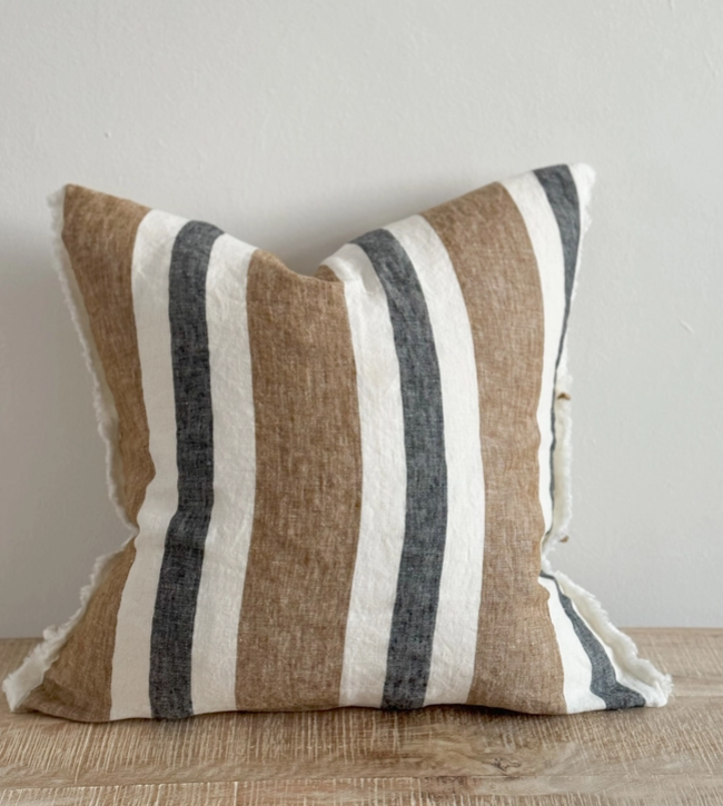 Navy and brown striped cushion cover with linen look fabric displayed on a wooden surface
