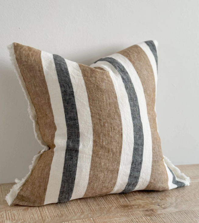Navy and brown striped cushion cover with linen look fabric displayed on a wooden surface
