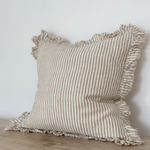 Light brown striped linen cushion cover with ruffled edges displayed on a wooden surface