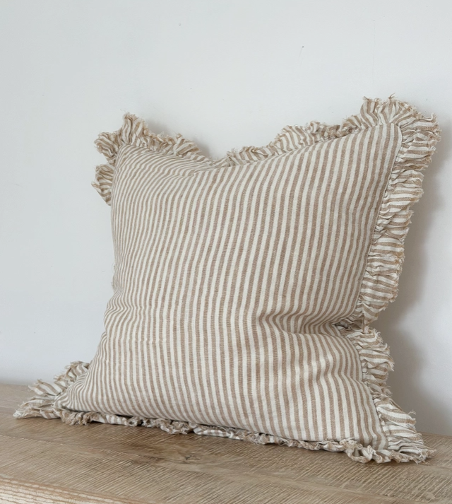 Light brown striped linen cushion cover with ruffled edges displayed on a wooden surface