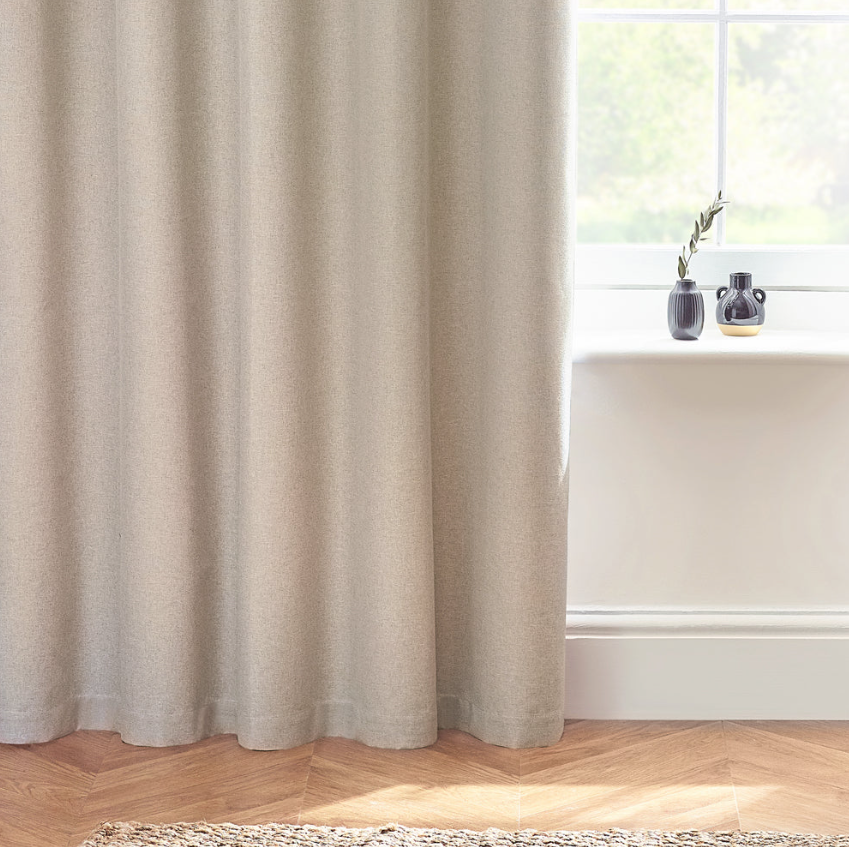 Beige curtain in a room with a window and decorative items on a windowsill.