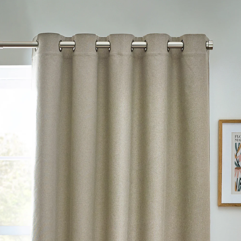 Beige curtain with metallic rings on a gray wall background