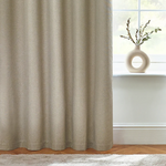 Beige curtain in a room with a vase on a windowsill