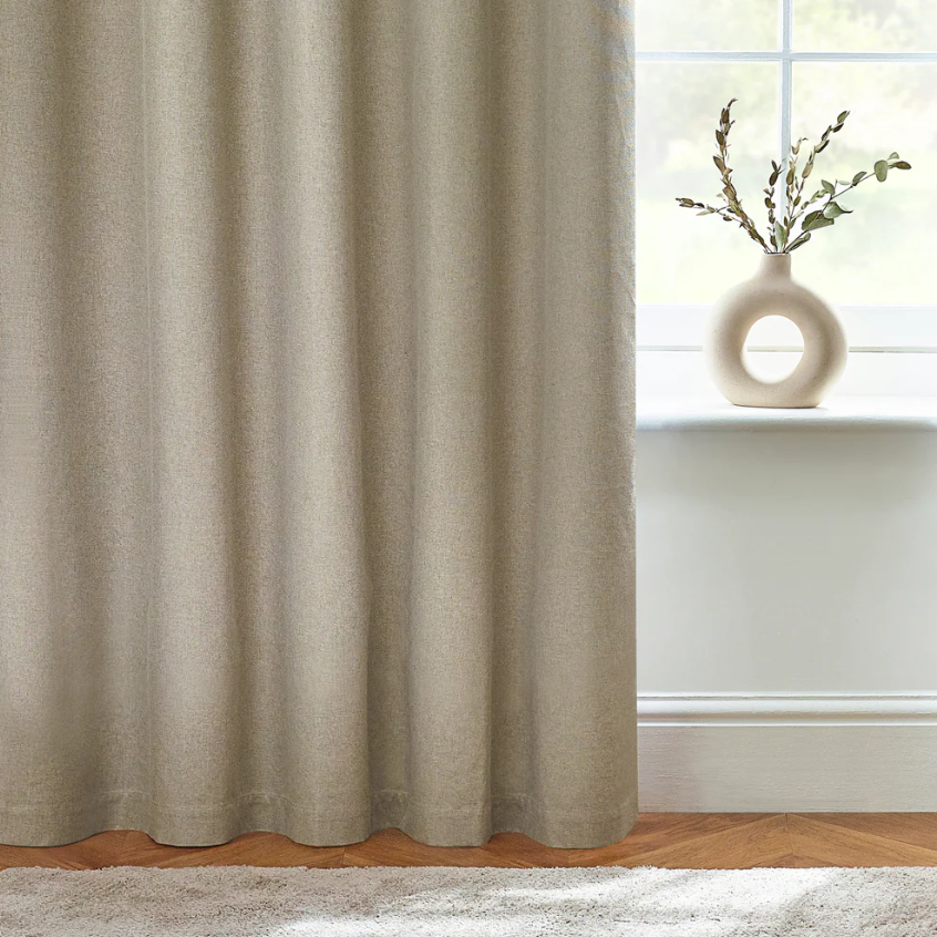 Beige curtain in a room with a vase on a windowsill