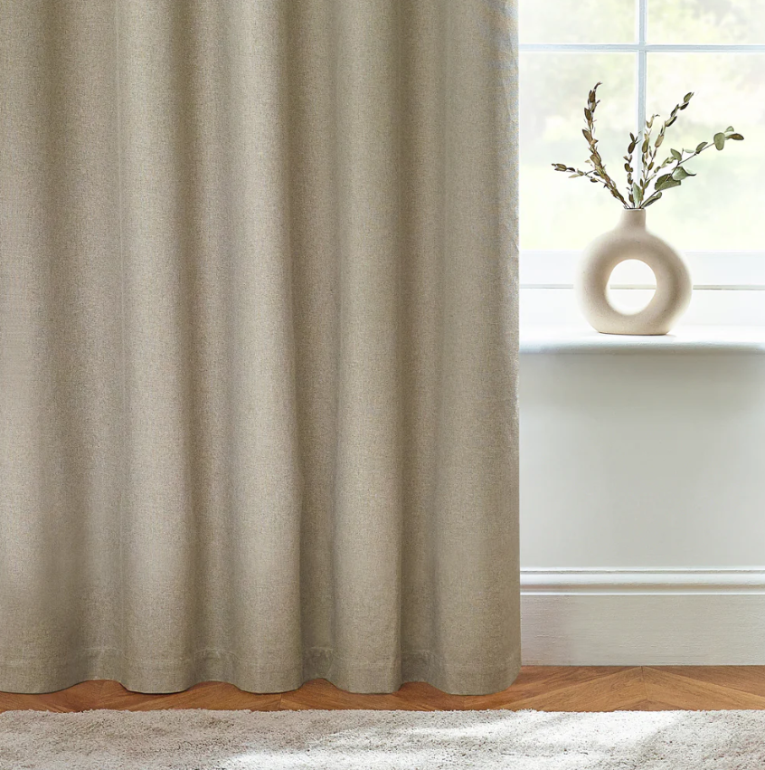 Beige curtain in a room with a vase on a windowsill