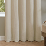 Beige curtains in a room with a wooden floor and a small table.