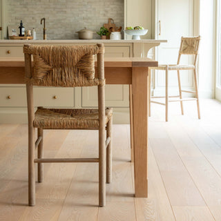 Wooden dining table with wicker chairs in a kitchen setting