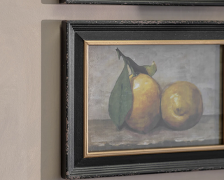 Vintage-style still life of two whole lemons with leaf, in a distressed black frame with gilt edge