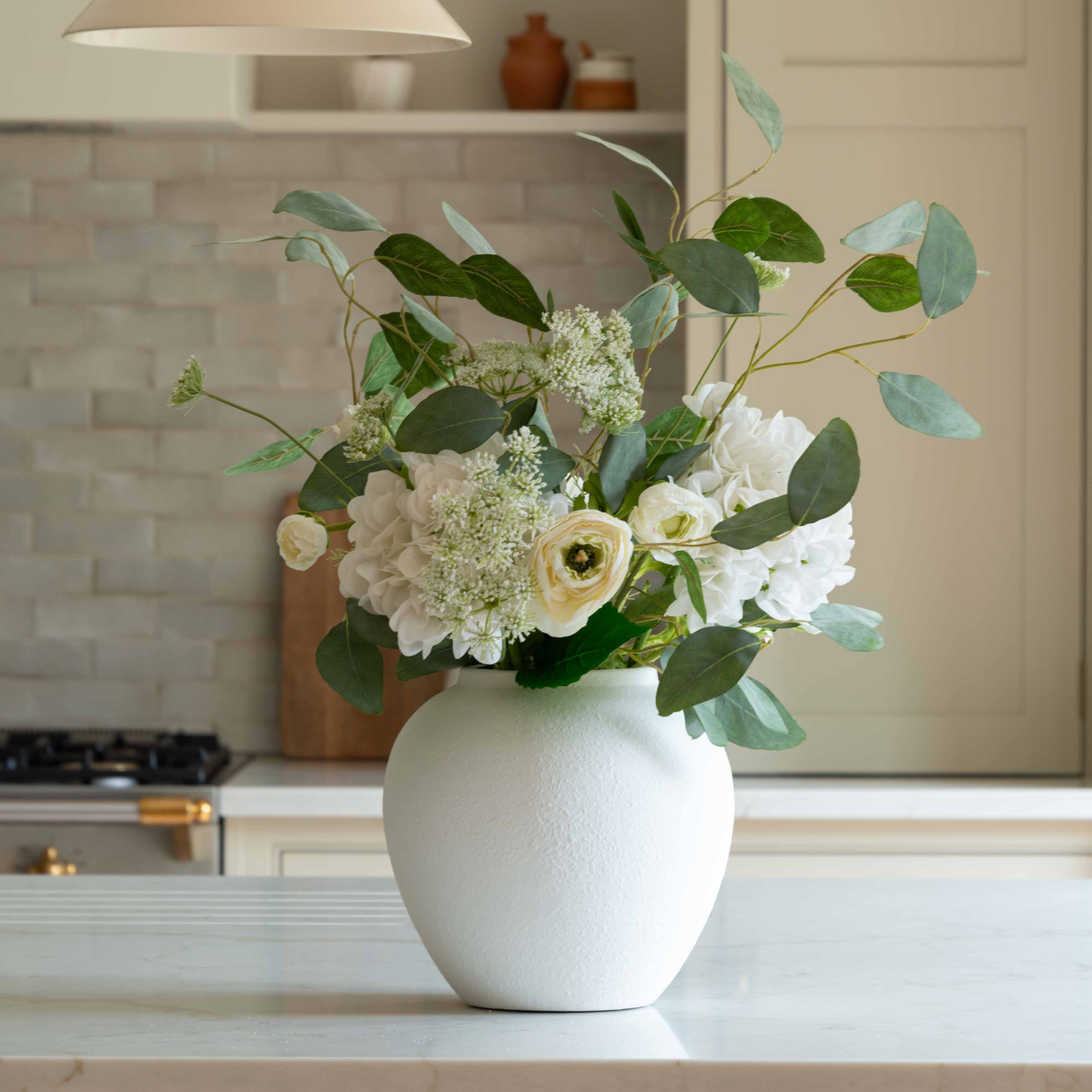 A gorgeous bouquet of white Ranunculus, white Hydrangea, white Meadow Spray and a foliage base of Silver Dollar Eucalyptus&nbsp;