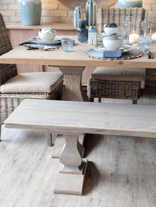 Dining table set with plates, cups, and bowls in a rustic setting.
