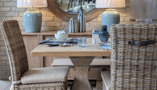 Dining room with wooden table, wicker chairs, and decorative items.