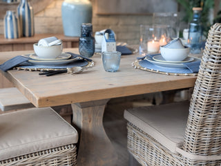 Dining table set with blue and white tableware, candles, and decorative items in a cozy indoor setting.