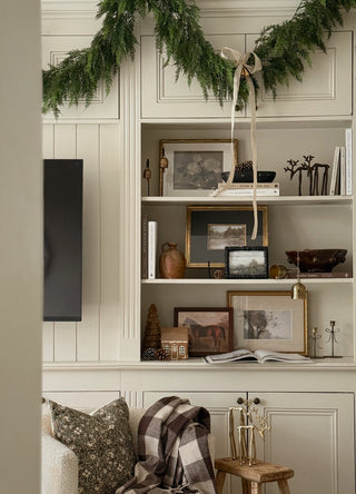 Faux cedar garland swagged along styled shelving in a traditional living room