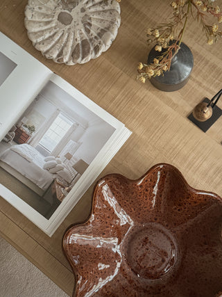 Terra brown ruffled ceramic dish styled on a table beside books and dried flowers