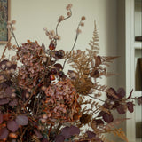 Decorative arrangement of dried flowers and leaves with a neutral background