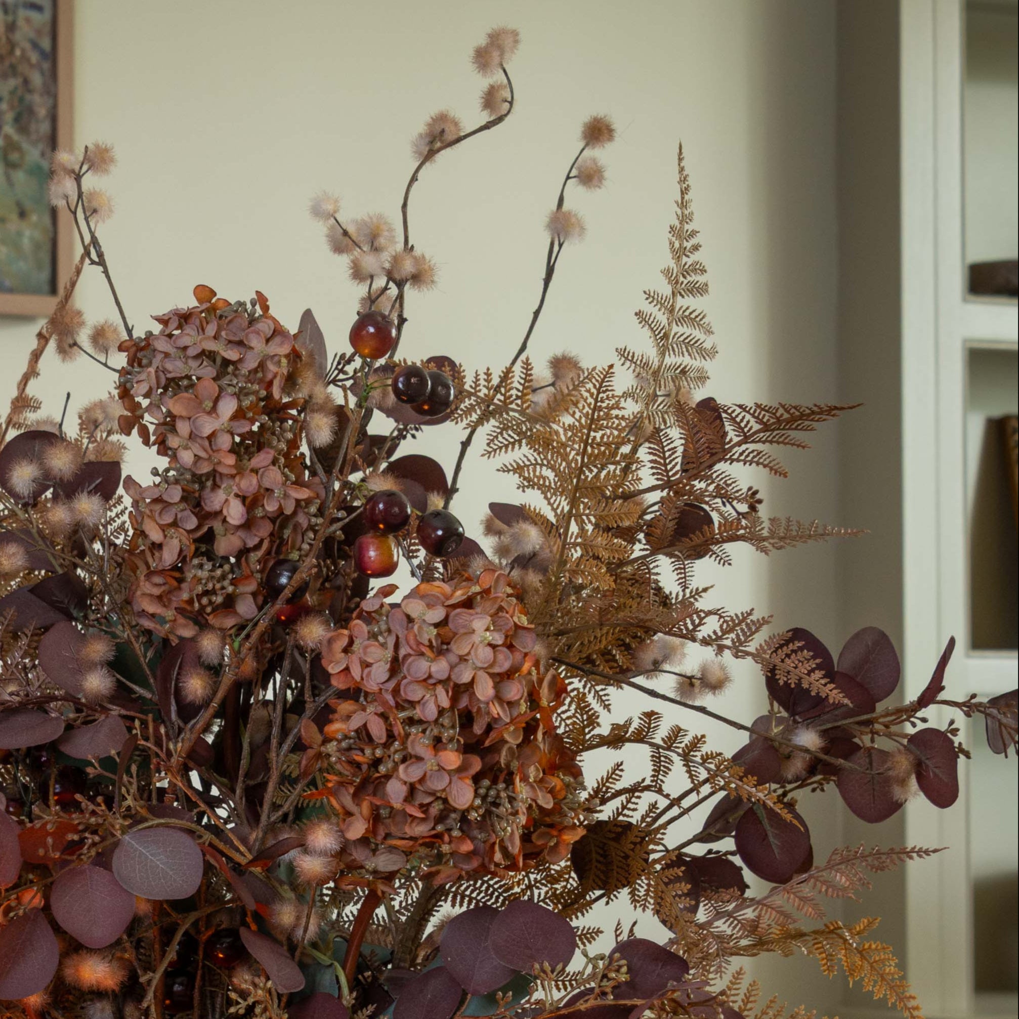 Decorative arrangement of dried flowers and leaves with a neutral background