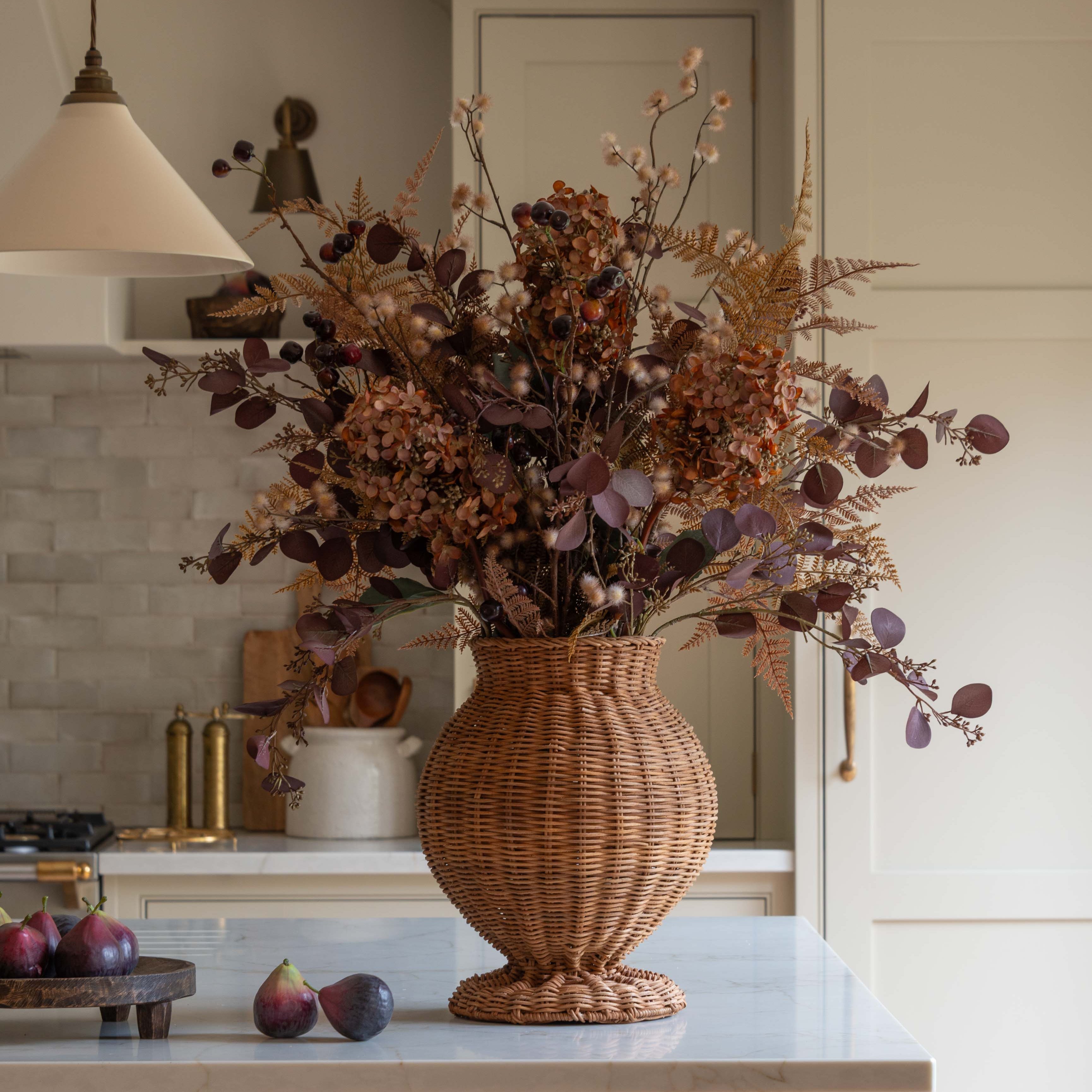 Artificial autumn bouquet in wicker vase on marble kitchen island