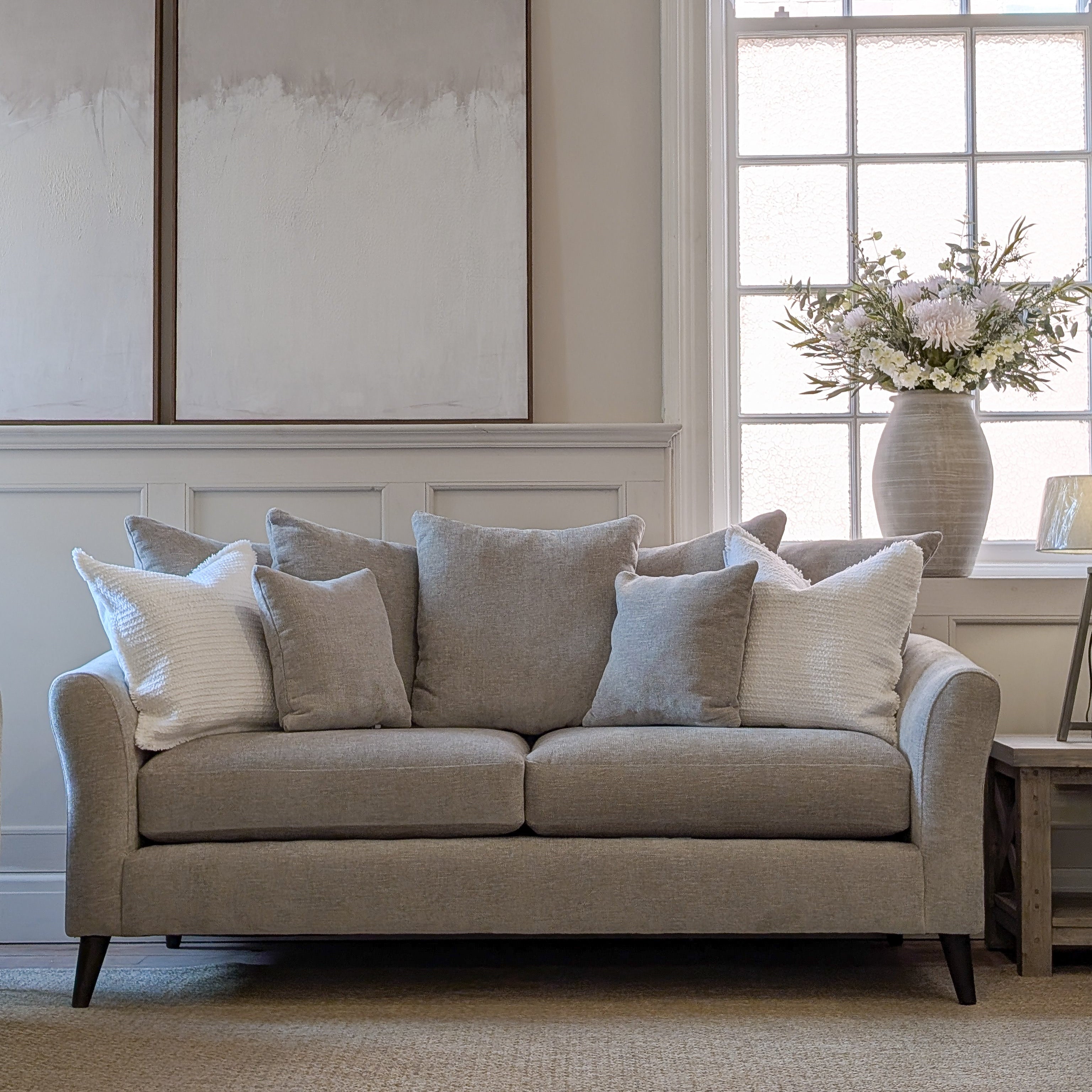 The Isla Pillow Back Sofa in Pebble Grey with layered scatter cushions and curved arms, made to order in six fabric options
