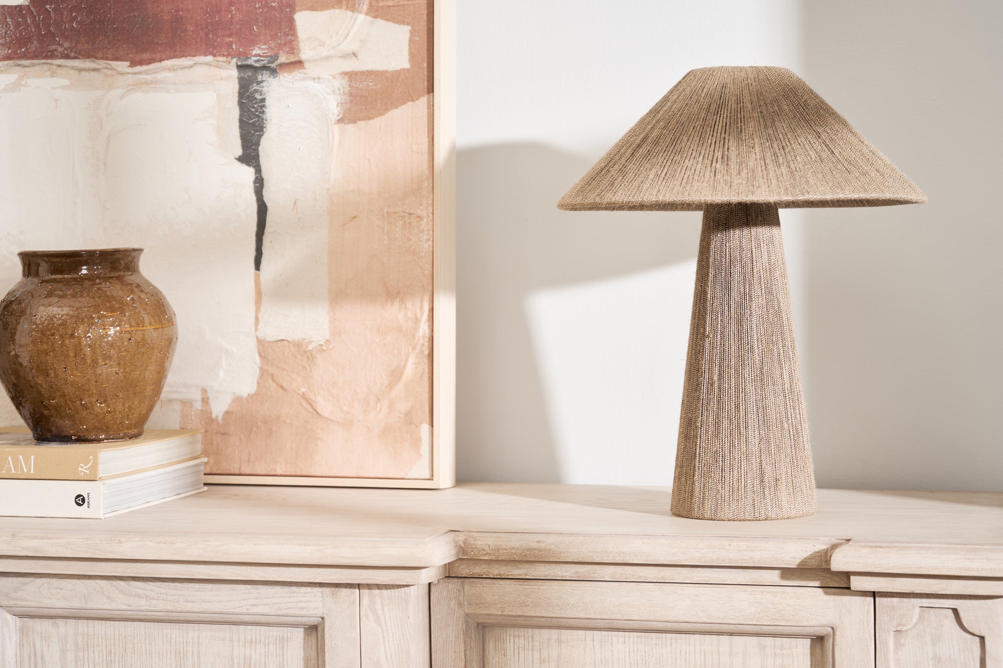 Natural jute table lamp with linen shade and tapered base on a wooden console