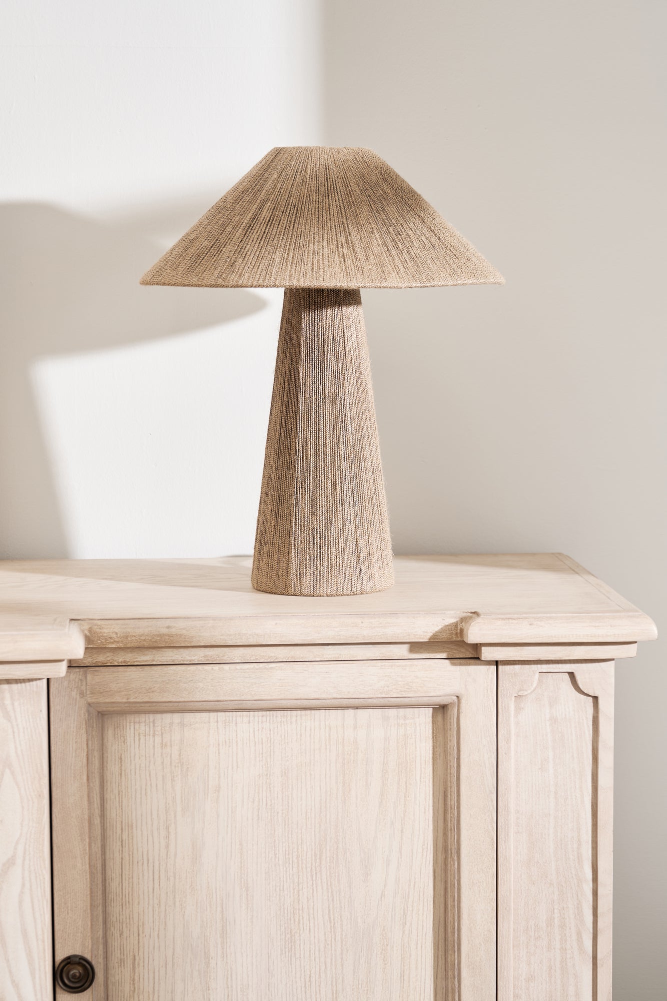 Natural jute table lamp with linen shade and tapered base on a wooden console
