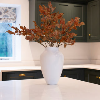 Three oak sprays arranged in a tall stoneware vase