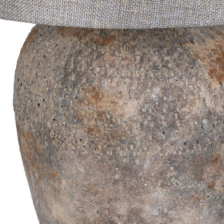 Close up of the pitted, weathered terracotta base in grey, ochre and rust tones