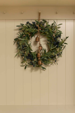 Green wreath with copper bells on a beige wall