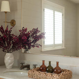 Bathroom vanity with a mirror, vase of flowers, and decorative bottles.