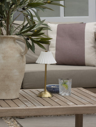 Outdoor setting with a wooden table, lamp, and decorative items on a patio.