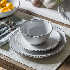 White ceramic dinnerware set on a wooden table with a neutral color scheme.