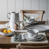 Dining table setting with ceramic dishes and a pitcher on a wooden table.